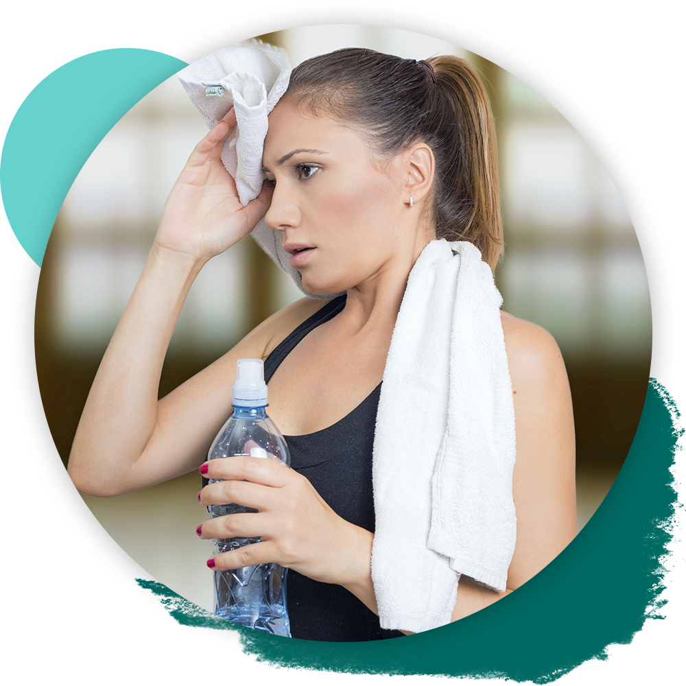 woman sweating after workout, with towels and water bottle