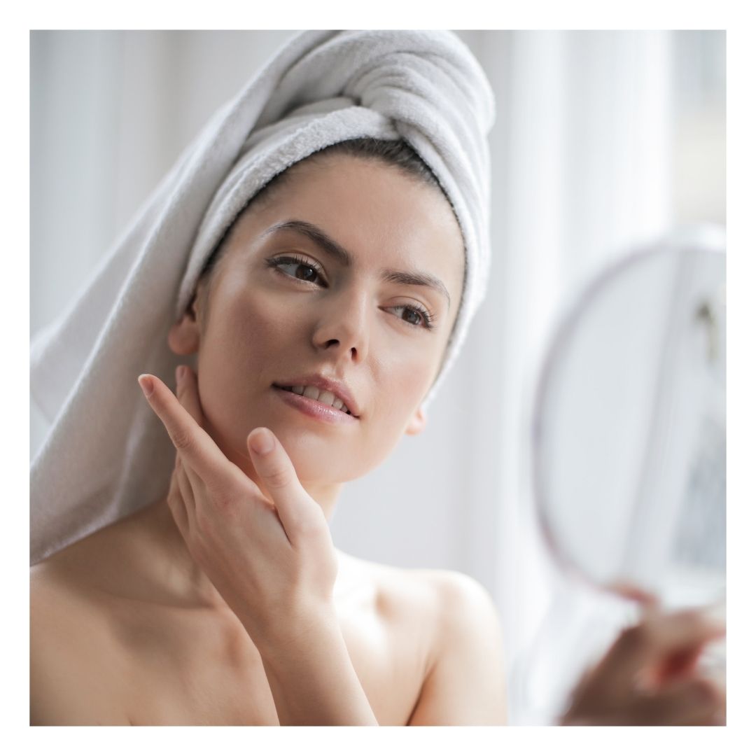 woman looking at skin in the mirror