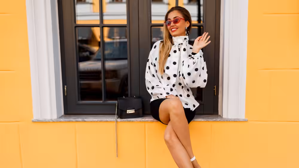 Smiling woman in polka dot blouse on windowsill